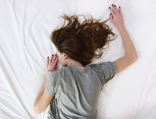 Arial picture of a woman laying on her stomach sleeping on white sheets