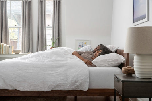 Couple cuddling in a bed made with white bedding