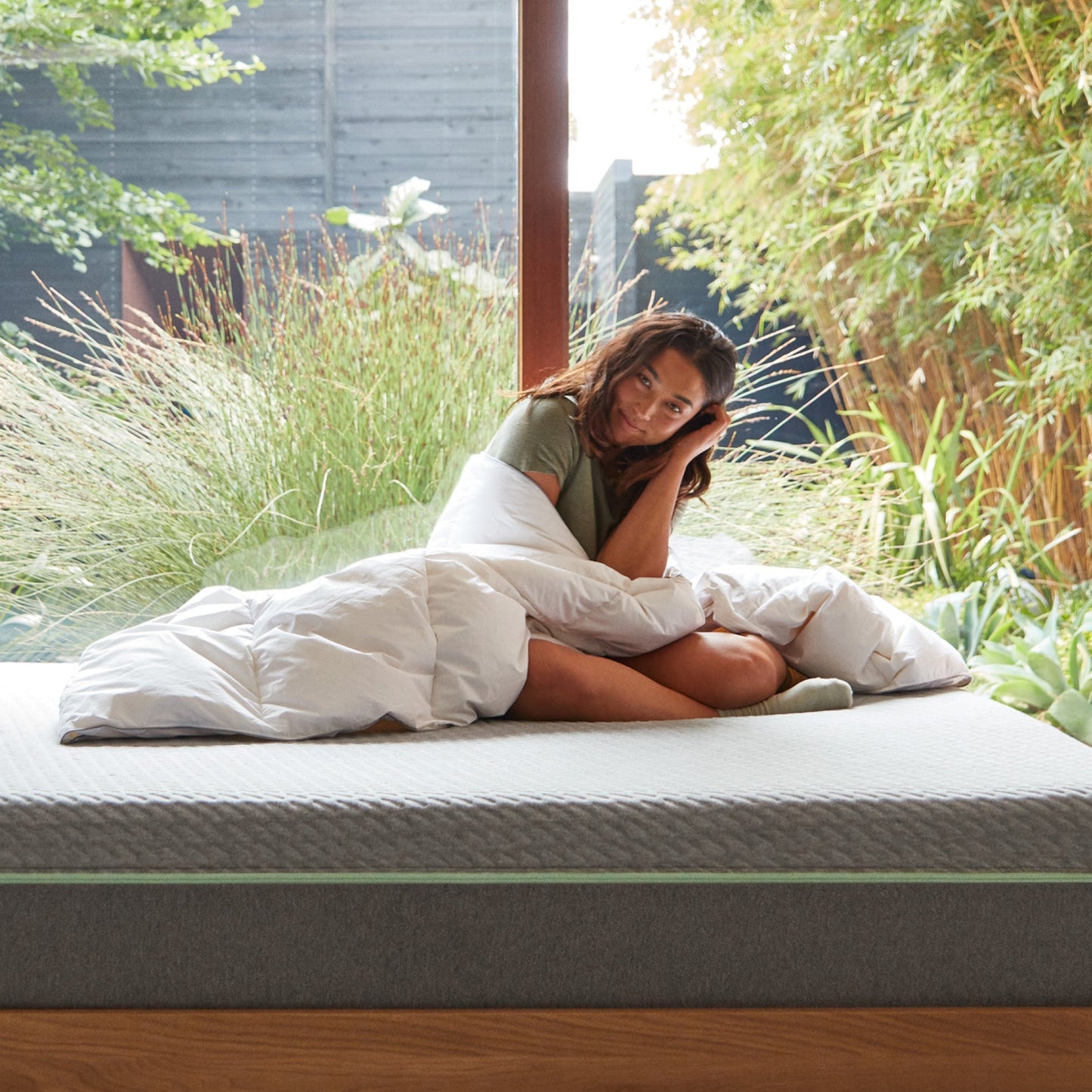 A woman on a bed wrapped in the Tuft and Needle Down Duvet Insert||weight:light