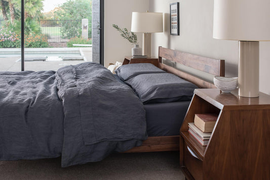 Tuft and Needle wood bed frame and mattress in a bedroom with a big sliding glass door
