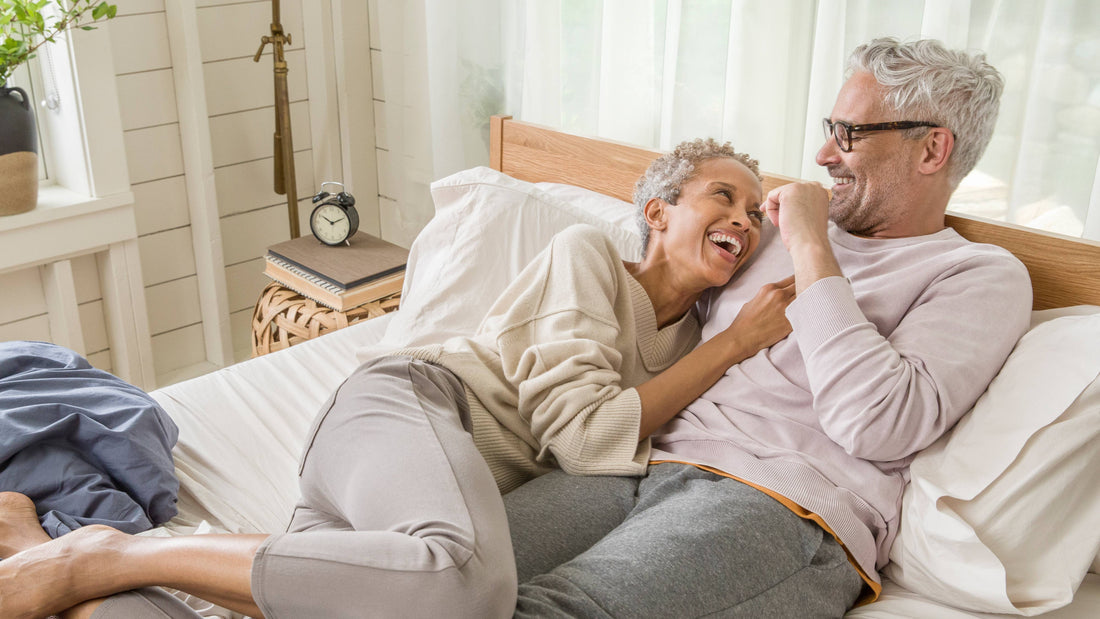 Older couple laying in bed and laughing while looking at each other