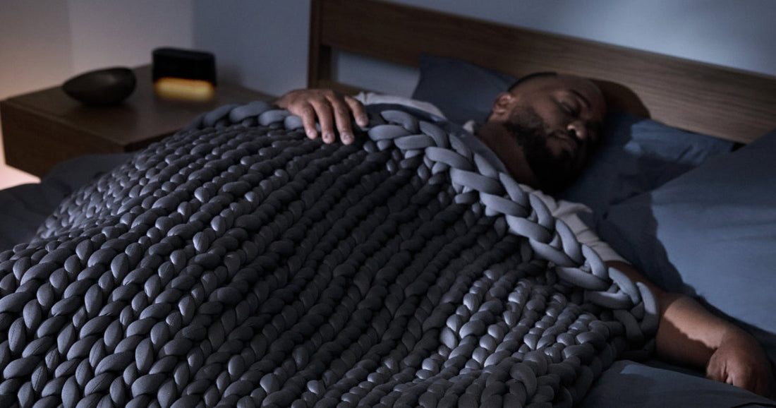 Man sleeping in a bed under the Tuft & Needle weighted blanket