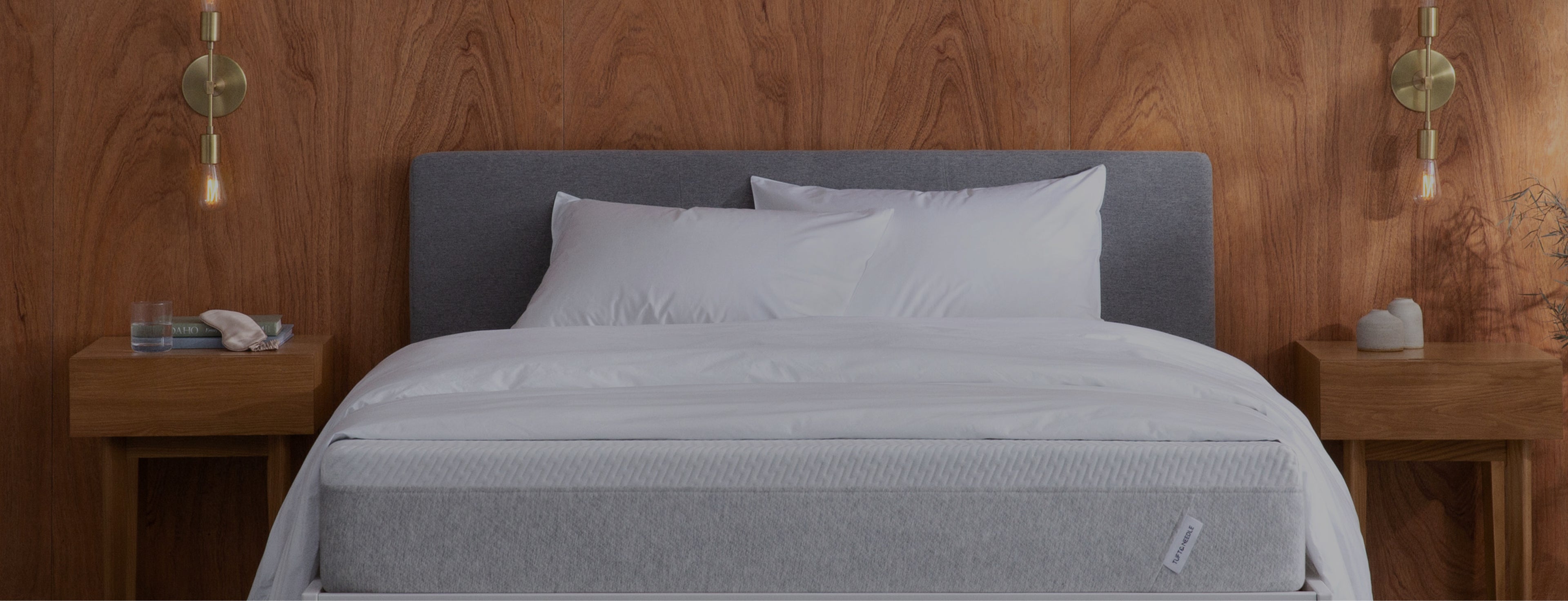Gray Tuft and Needle mattress on a bed with wooden headboard and nightstands.