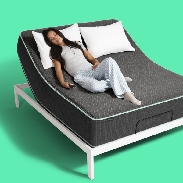 Woman laying on her back on a Tuft & Needle mattress elevated at the head of the bed as she lays with a pillow under her head.