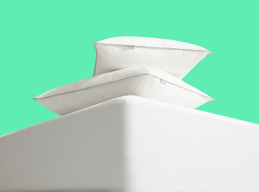 Two tuft and needle pillows on top of a mattress protector