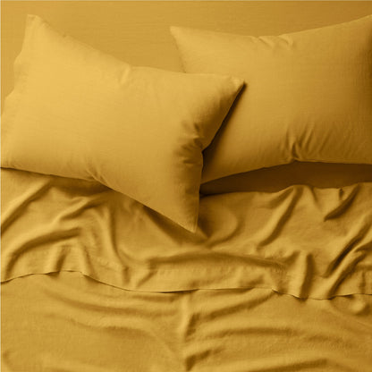 Two pillows on a bed dressed in the Tuft and Needle Hemp Pillowcase Set||color:honeycomb