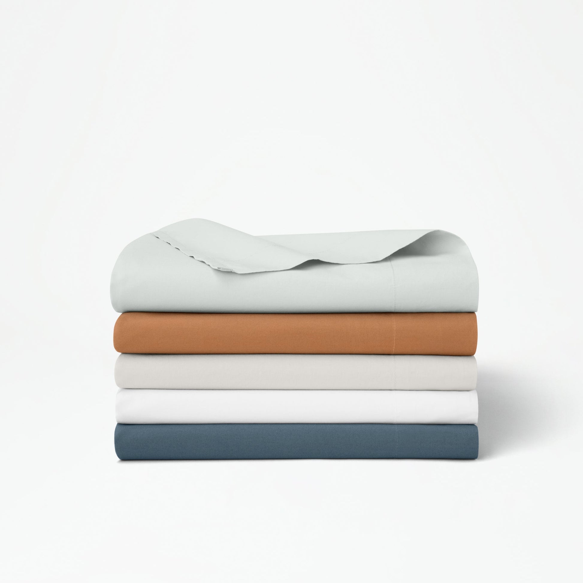 The Tuft and Needle Percale Duvet Cover Set folded and stacked on a white background||color:canyon
