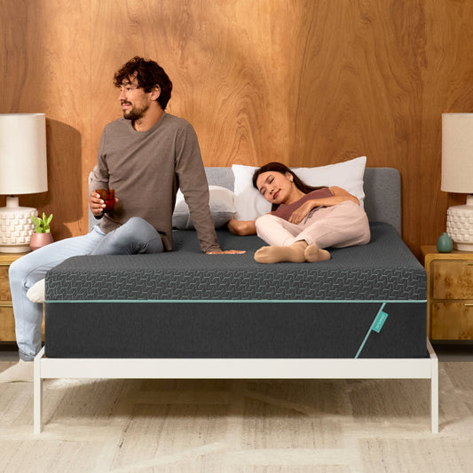 Man and woman laying on a Tuft & Needle Mint Hybrid mattress sitting in a white bedframe