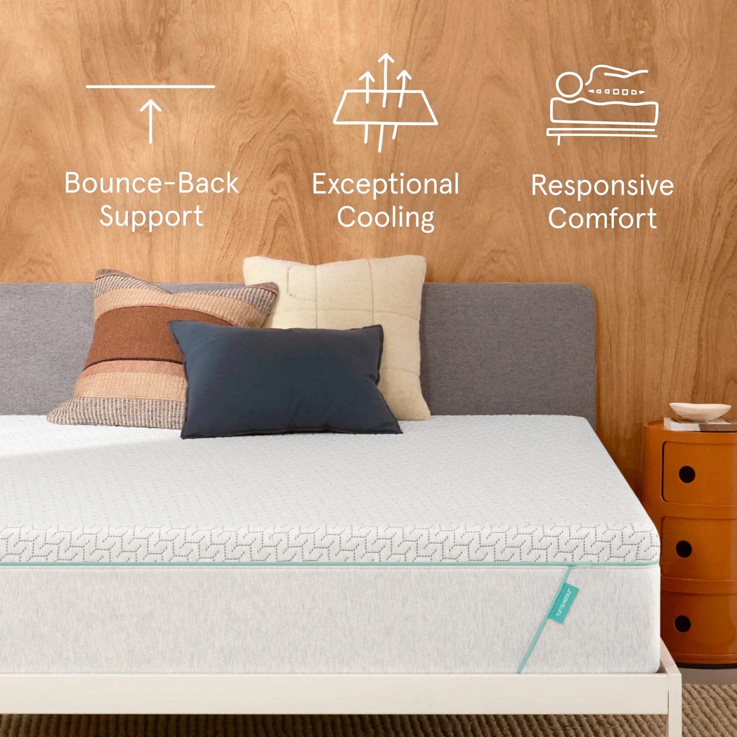 Tuft & Needle Original Hybrid Mattress sitting in a brown bedframe with 2 pillows on top of it and a brown blanket with a chart on the wall showing icons reflecting Bounce-Back Support, Exceptional Cooling and Responsive Comfort