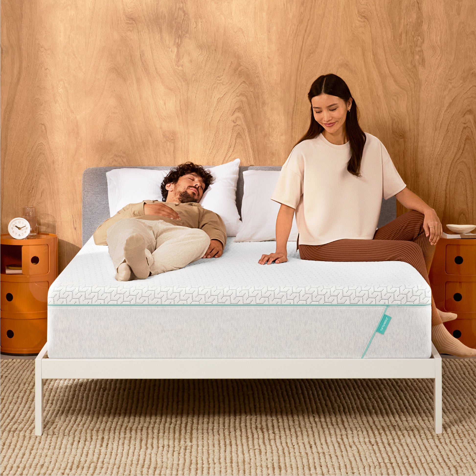 Man and woman laying on a Tuft & Needle Original Hybrid mattress sitting in a white bedframe