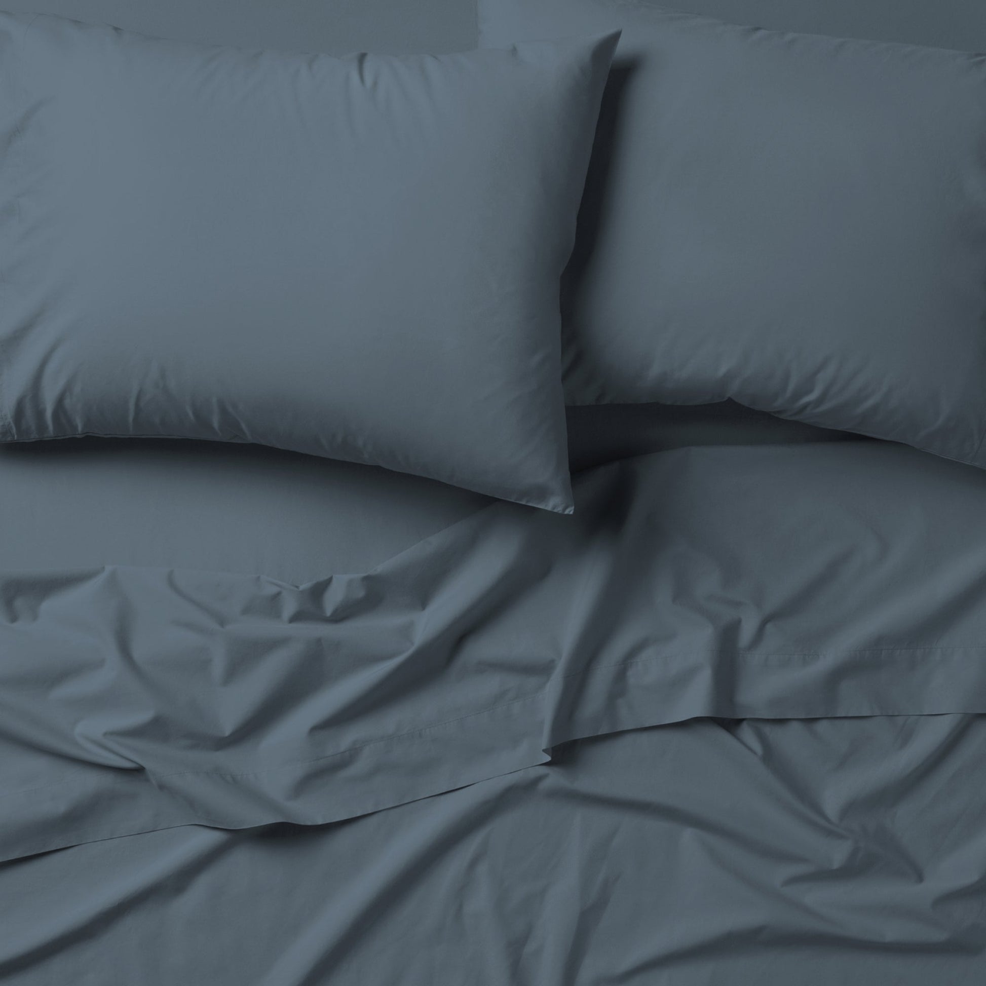 The Tuft and Needle Classic Percale Sheet Set, 2 pillows on top of a sheet on a mattress || color: Slate
