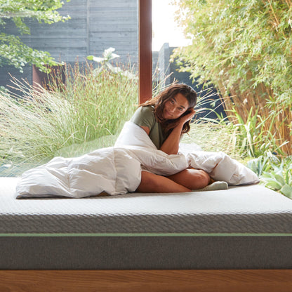 A woman on a bed wrapped in the  Tuft and Needle Down Duvet Insert||weight:light