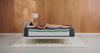 Woman rolls on to her side on a mattress that shows the inside layers to display pressure relief. 